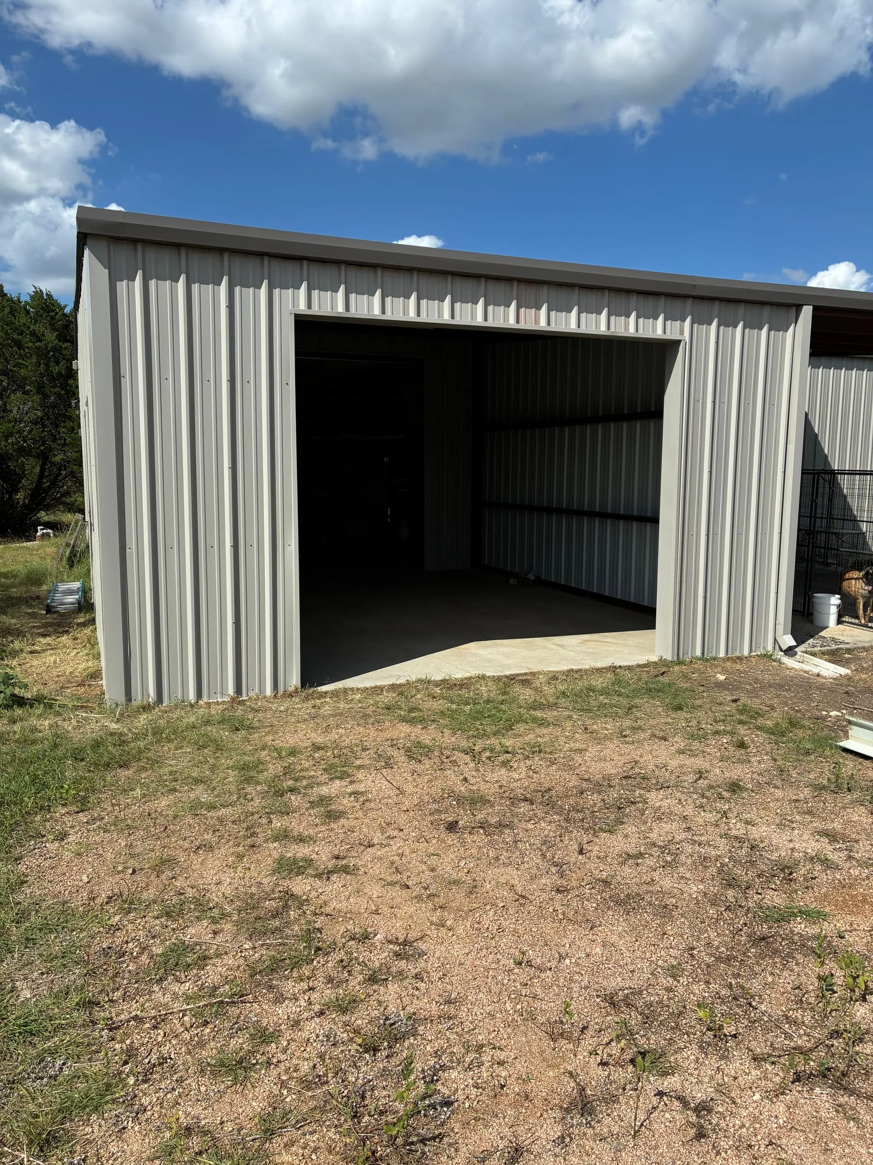 Large shop opening and metal wall panels beside the concrete floor.