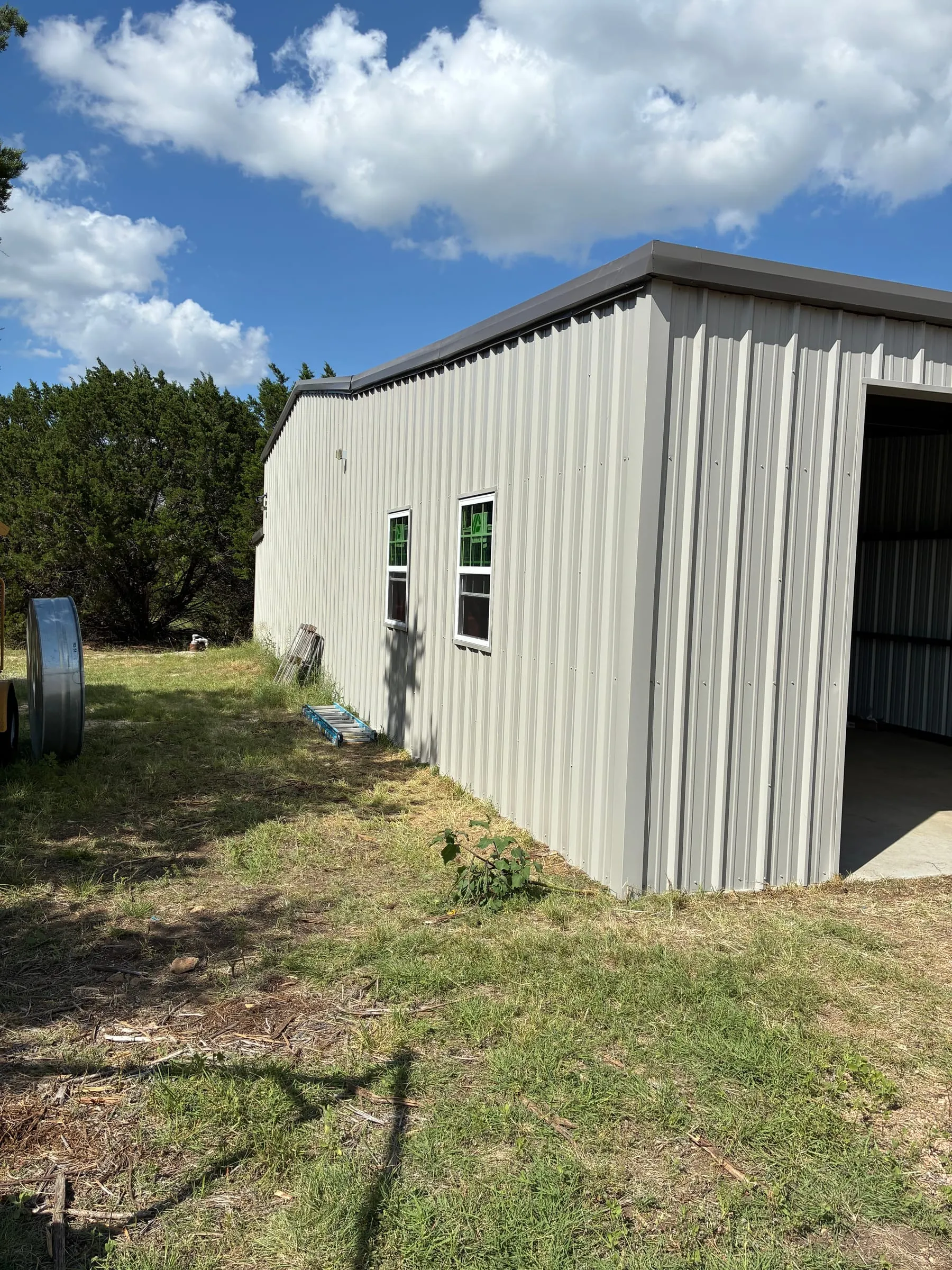 Metal-sided shop wall with two windows and a wide open bay.