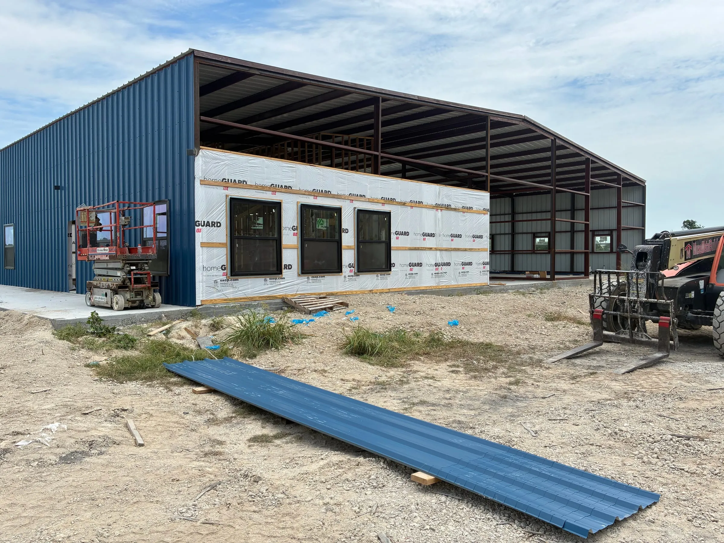 Home-and-shop structure with blue siding and wrapped living-area walls.