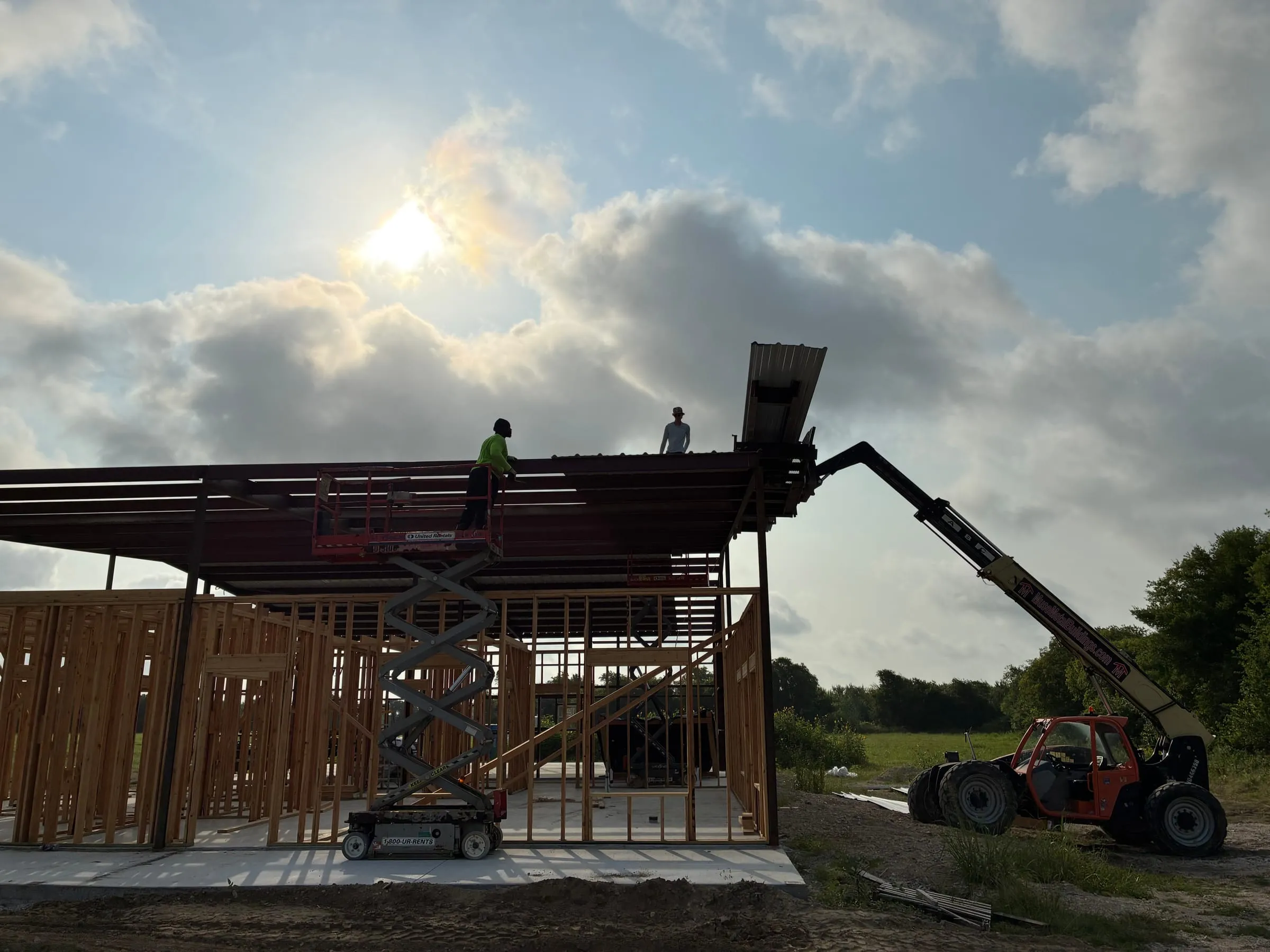 Crew members guide metal roof panels across the framed home.