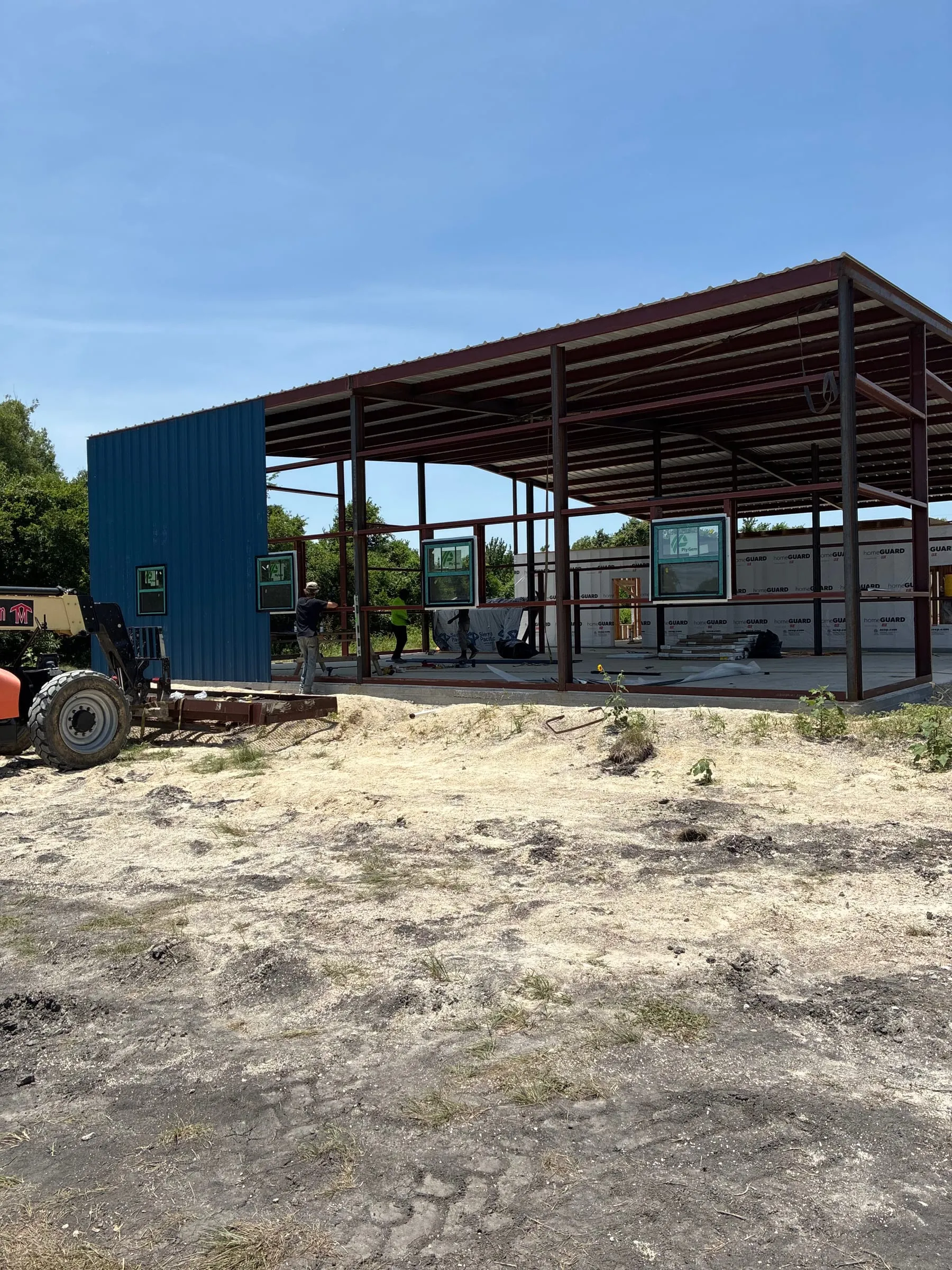 Exterior work area beside the framed and roofed home structure.