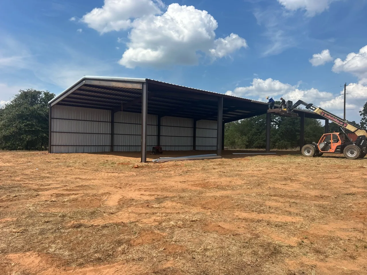 Steel hay barn under construction in Whitney, with roof and wall panels installed.