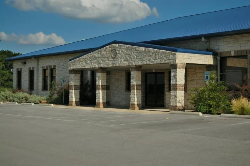 Commercial office building featuring a blue standing-seam metal roof and stone portico.