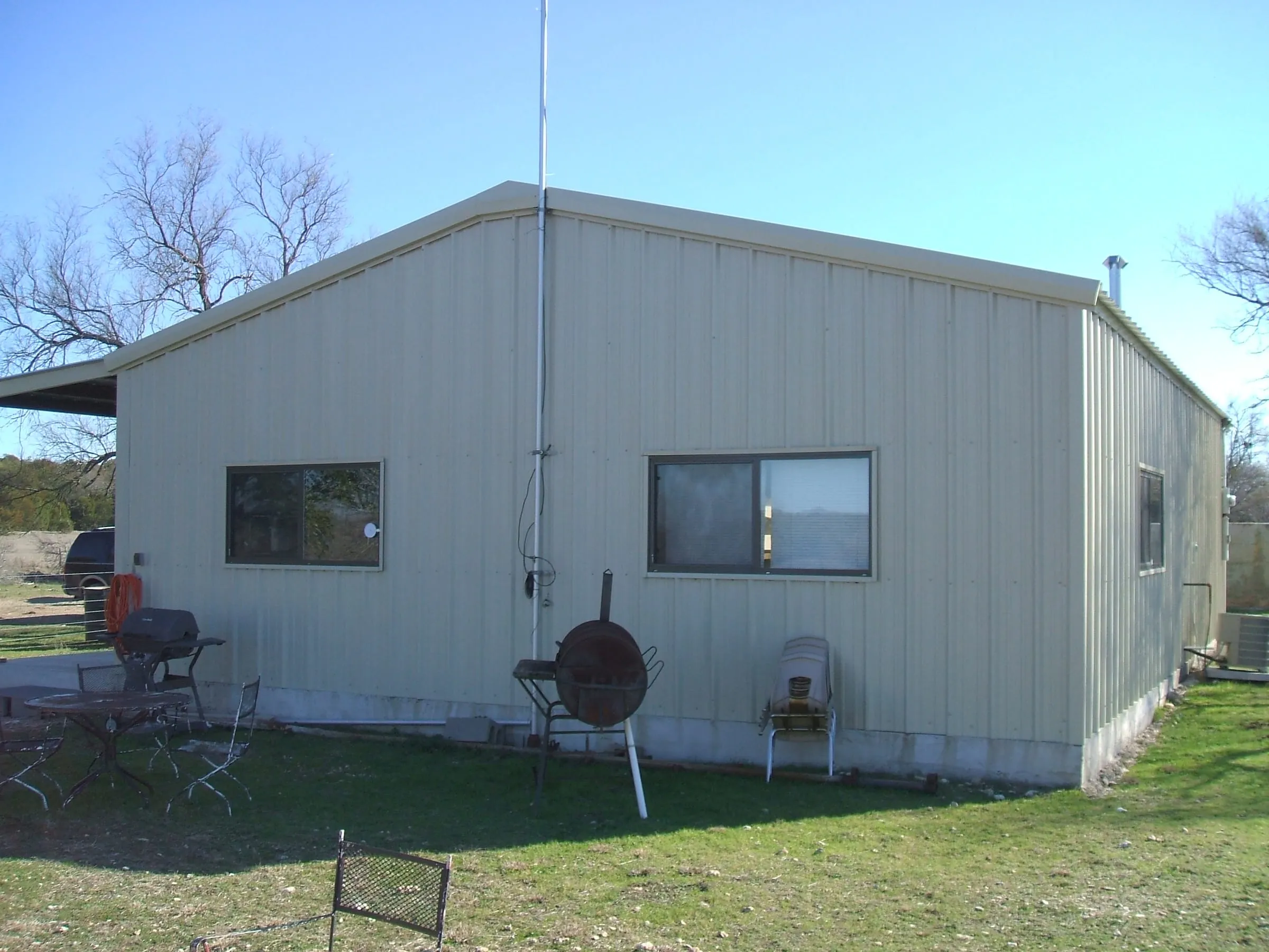 Economy metal deer cabin with white siding on open ranch land.