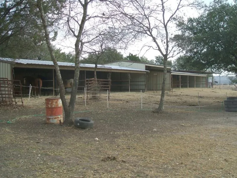 Long ranch barn with metal roof and livestock pens.