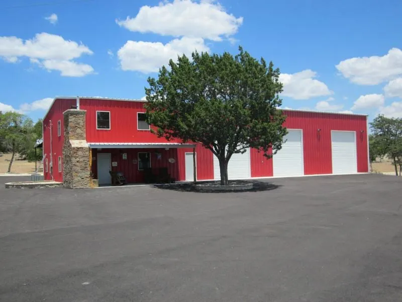 Red custom steel home with metal siding and stone entry.