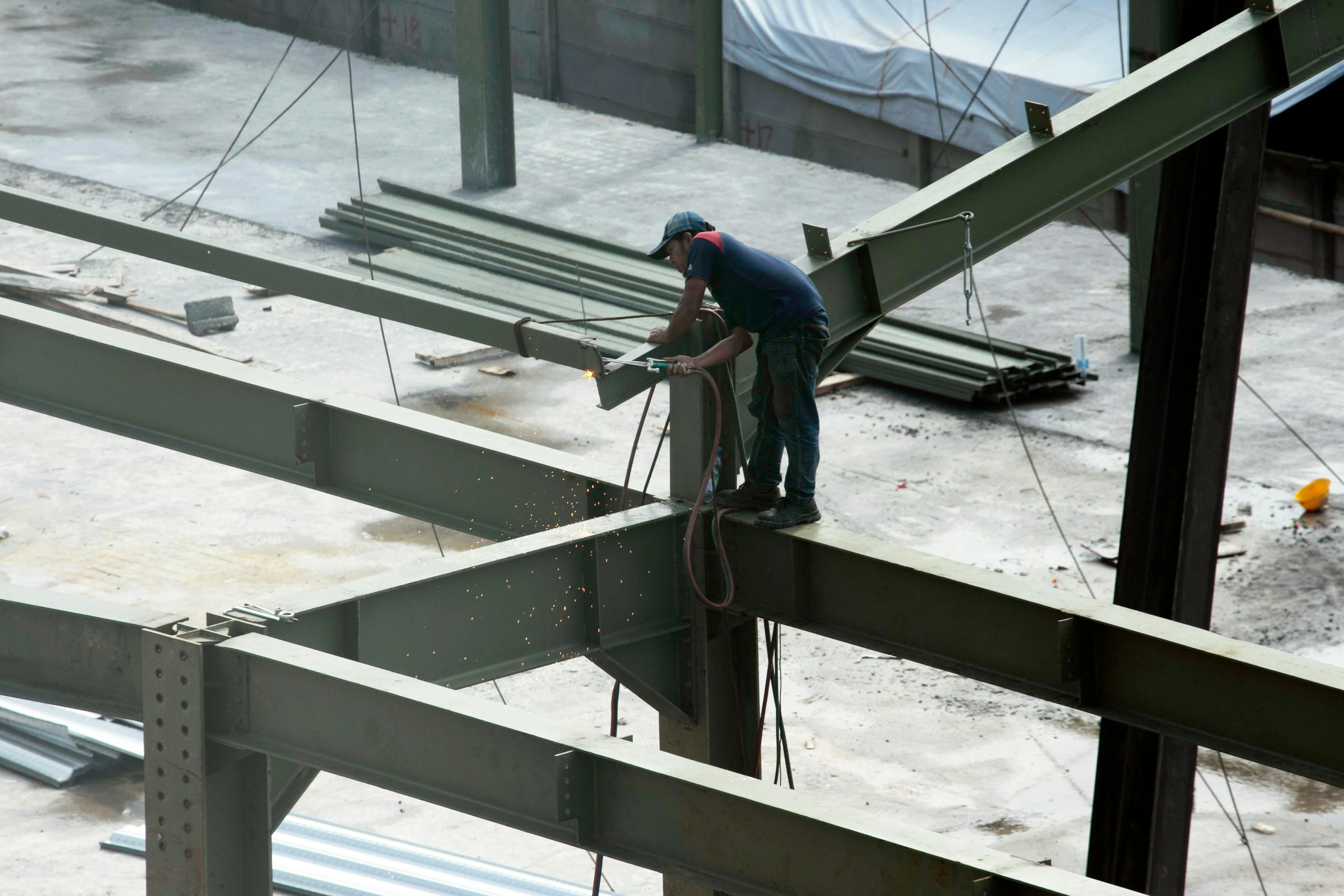 Muse crew member working steel on a metal building frame.